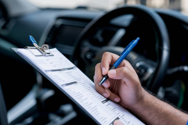A car maintenance worker is checking a list of the car interior for a workshop customer.